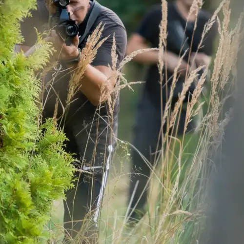 gracze paintballa laserowego ukrywający się za krzakiem